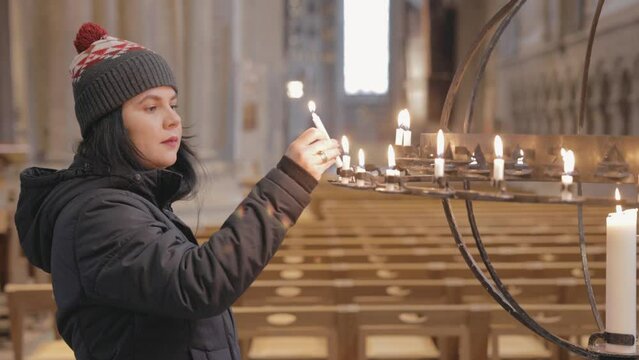 Woman Lighting A Votive Candle At The Linkoping Cathedral In Sweden. - medium