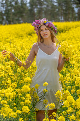 Fototapeta premium Girl with a wreath in a rapeseed field