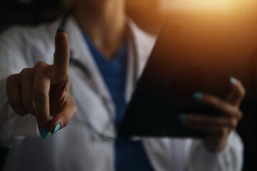 Female Doctor Wearing Scrubs In Hospital Corridor Using Digital Tablet