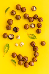 Pile of raw macadamia nuts with leaves. Healthy protein snack background