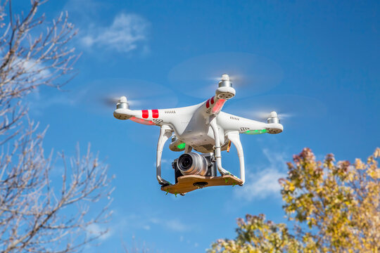 FORT COLLINS, CO, USA, November 2, 2014:  Airborne radio controlled DJI Phantom 2 quadcopter drone flying over trees with  the Panasonic Lumix GM1 camera mounted on a home made platform.