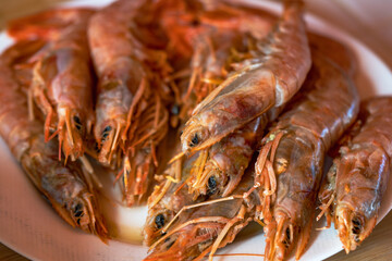 White plate with raw red prawns ready to cook for fideua or paella
