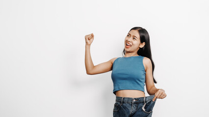 Young pretty asian chinese woman weight loss with oversize big blue jean pants, isolated background.