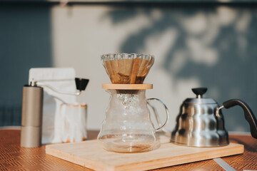 Making filtered drip coffee in coffee shop. Close up of brewing a drip hot espresso, pour over coffee with hot water and filter paper at home.