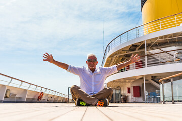 happy handsome middle aged man posing sitting on the deck of a cruise ship