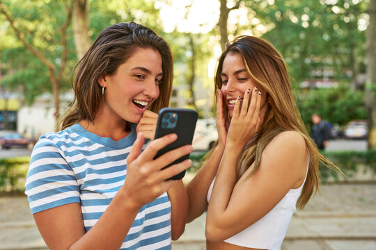Friends laughing at their phones in the park.