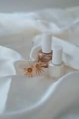 Nail polish bottles on white silk background, beauty and fashion concept