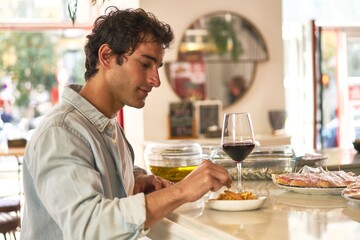 Young man drinking a wine in a bar 