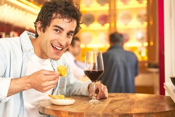 Young man enjoys wine tasting with Spanish tapa.
