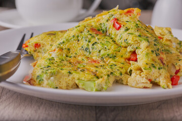 Broccoli and onion omelette shot close up on a white plate.