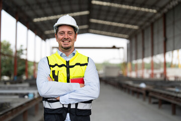Portrait of male civil engineer wearing safety vest with white helmet standing arms crossed at...