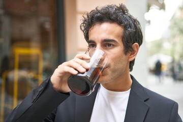 Young businessman enjoying a refreshing cola drink while networking at a sophisticated bar.