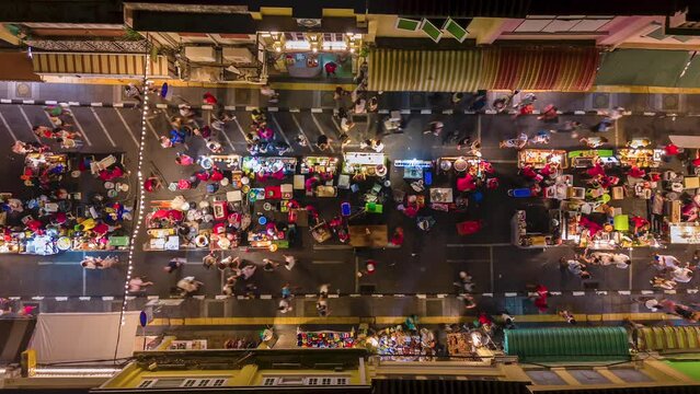 Aerial time-lapse of the vibrant night market in Phuket Old Town. Colorful street food stalls, bright lights, and crowds of tourists. Thailand.