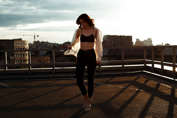 Relaxed young girl walking on roof terrace on background of cityscape