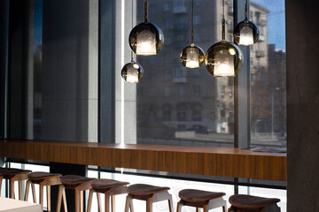 Roller blinds in the cafe. Solar shades black color in the urban style interior. Wooden table near...