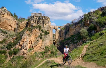 Cercles muraux Ronda Pont Neuf nice, active senior woman riding her electric mountain bike below the famous New Bridge of Ronda, Andalusia, Spain