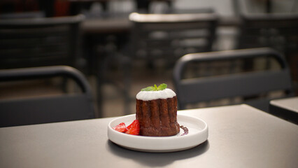 Caneles de bordeaux - traditional French sweet dessert, with sugar or white glazed chocolate on top and strawberry garnish on side 