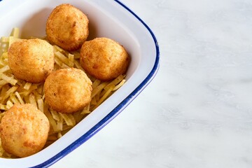 Top view closeup of fried cheese balls on little potato chips in a bowl