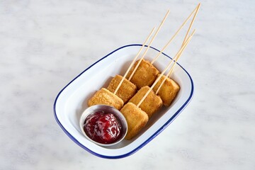 Closeup of mozzarella in carrozza, fried cheese on sticks next to a sauce