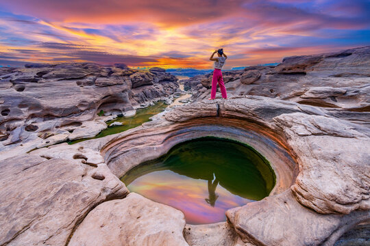 Young female tourists stand to watch the sunrise at Sam Phan Bok, Ubon Ratchathani, Thailand