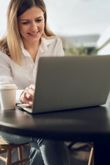 Smiling female freelancer working on laptop in cafe