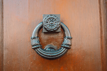 An antique iron door knocker on a wooden door. Pisa, Italy