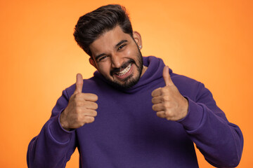 Like. Indian young man in hoodie raises thumbs up agrees with something or gives positive reply...