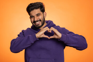 Man in love. Smiling bearded indian man 25 years old makes heart gesture demonstrates love sign...