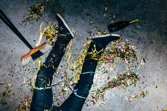 Crop drunk man with confetti on floor during party