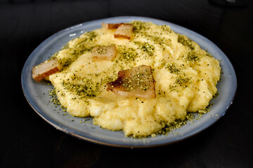 Creamy Italian polenta with bacon, pork crackers or pancetta, sprinkled with spices,