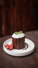 Caneles de bordeaux - traditional French sweet dessert, with sugar or white glazed chocolate on top and strawberry garnish on side 