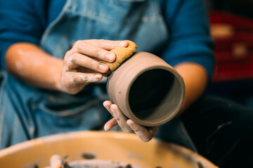 Fototapeta na wymiar Craftsman potter making jug of clay on potter wheel circle in workshop