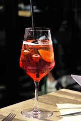 Aperol cocktail in a large glass with a straw inside