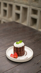 Caneles de bordeaux - traditional French sweet dessert, with sugar or white glazed chocolate on top and strawberry garnish on side 