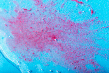 Obraz premium Red particles in transparent liquid with bubbles on blue background. Laboratory studies. Cosmetics, gel, transparent texture, lotion. Selective focus, defocus
