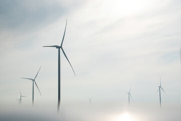 Windmills towers with operating rotor blades produce alternative energy in countryside. Wind...