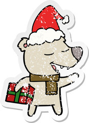 distressed sticker cartoon of a bear with present wearing santa hat