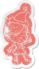 cartoon distressed sticker of a squinting girl wearing santa hat