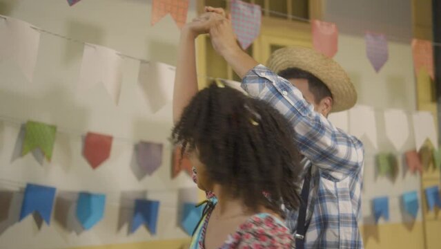 Festa Junina in Brazil, happy brazilian couple dancing at arraial party in caipira style clothes