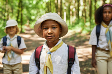 Waist up portrait of young black boy as boy scout wearing uniform outdoors in forest - obrazy, fototapety, plakaty