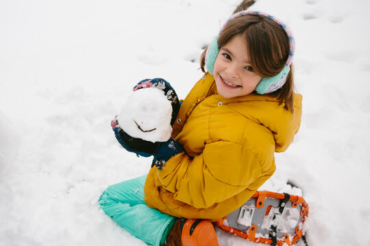 Girl in snowshoes makes a snowball