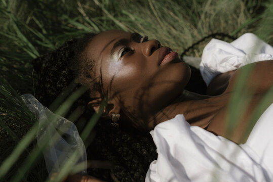 Relaxed black woman lying on grass in nature
