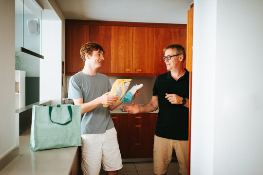 Father and son unpacking groceries in kitchen together
