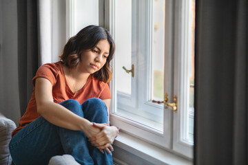Fototapeta na wymiar Seasonal Depression. Upset Pensive Young Arab Woman Sitting Near Window At Home