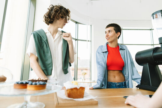 Young  Finely Dressed Couple's Discussion in Cafe in Front of Barista