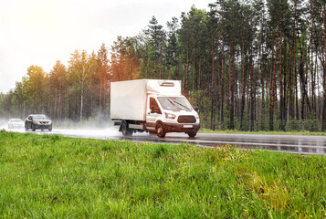 Refrigerated van transports perishable cargo of confectionery. The truck drives on a wet highway in...