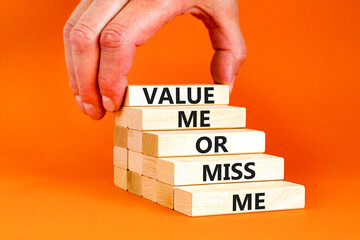 Value or miss me symbol. Concept words Value me or miss me on wooden block. Beautiful orange table orange background. Businessman hand. Business psychological and value or miss me concept. Copy space.