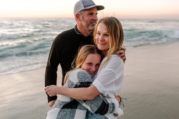 Obraz premium Smiling family hugging at the beach