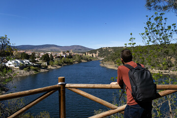 Fototapeta premium Man looking towards the town of Buitrago del Lozoya at the Pinarcillo viewpoint overlooking the Lozoya River.