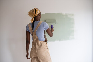 Black woman smearing green paint on white wall